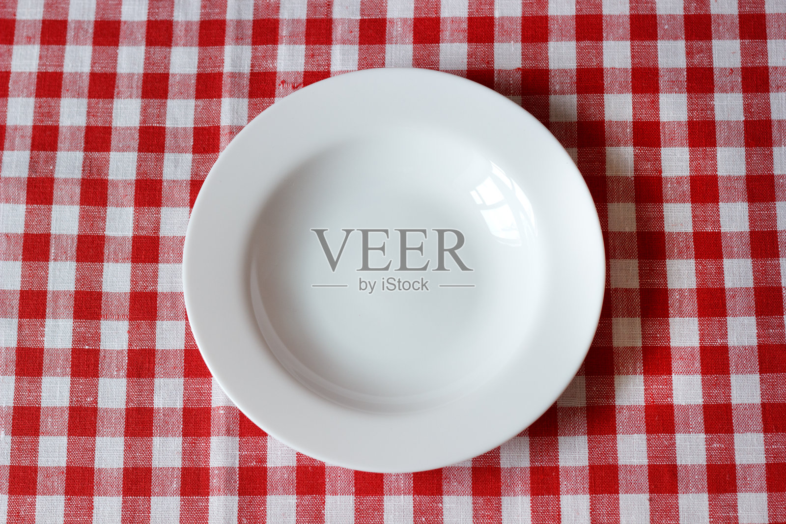 一个空盘子放在红白相间的桌布上照片摄影图片