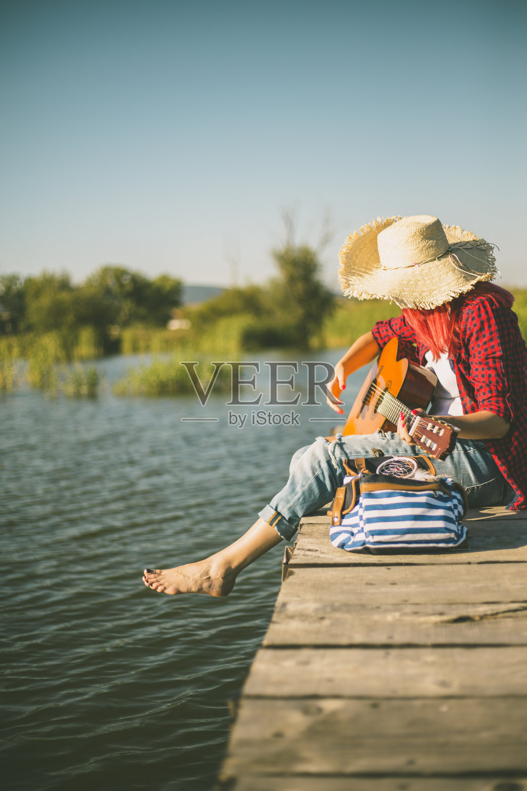 年轻女子坐在码头上弹吉他照片摄影图片