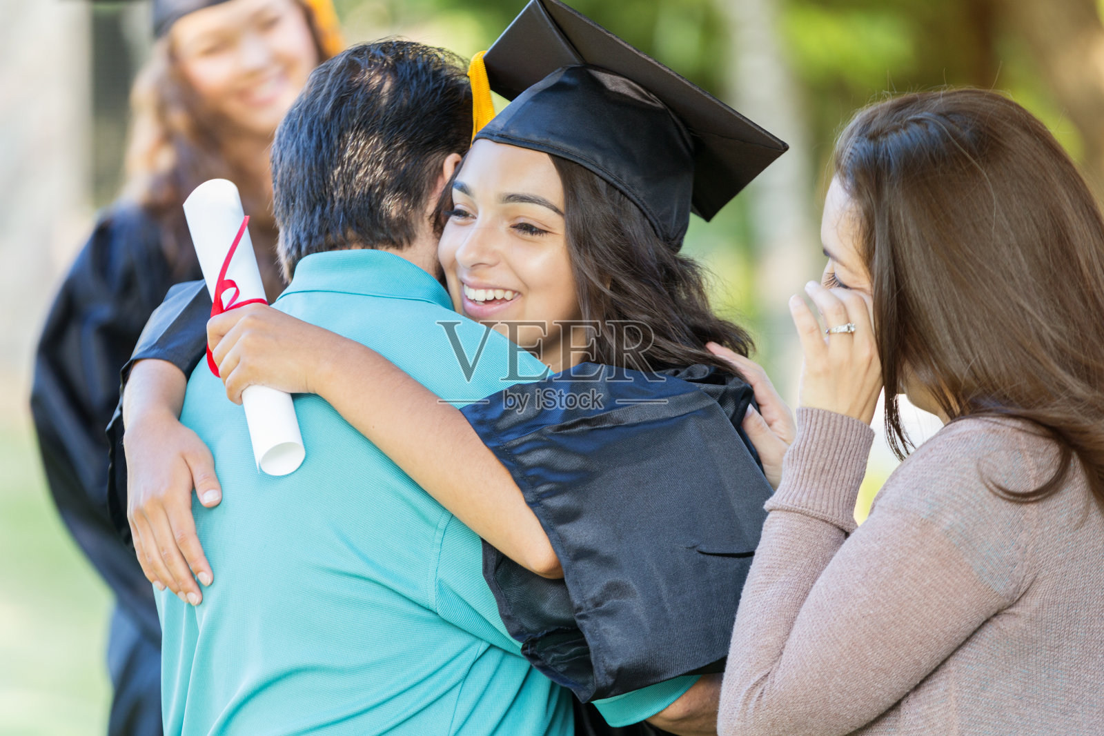 大学毕业生拥抱爸爸，妈妈骄傲地看着照片摄影图片