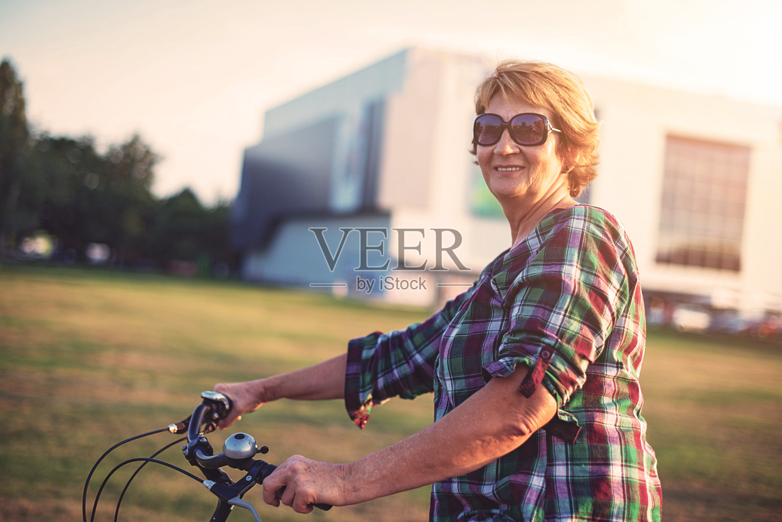 微笑成熟的女人在放松骑自行车在城市照片摄影图片