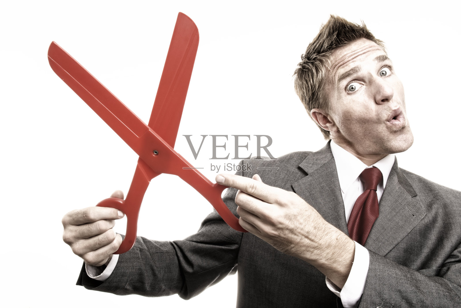 商人拿着一把红色的大剪刀剪啊剪照片摄影图片