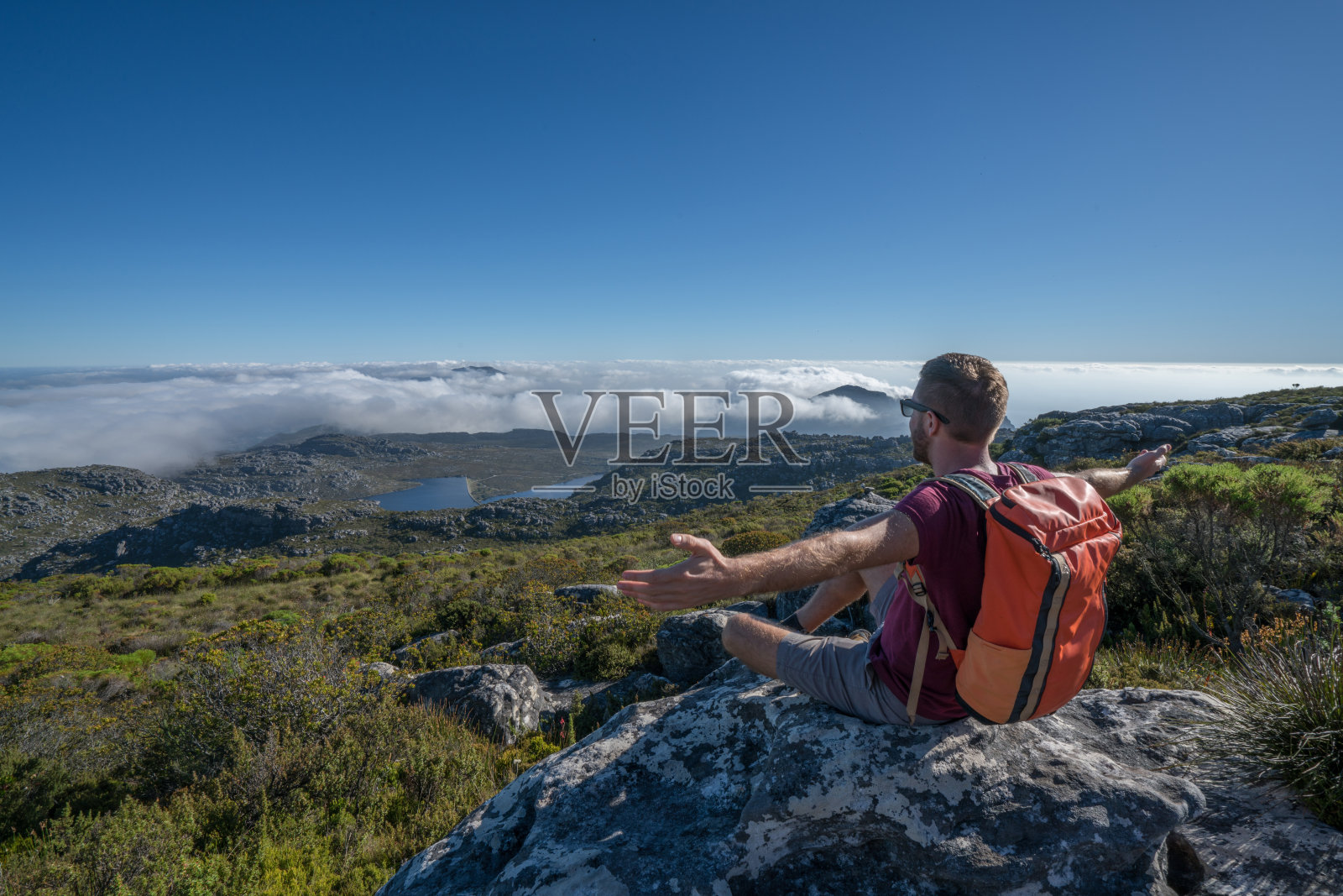 年轻男子在开普敦徒步旅行，在山顶伸开双臂照片摄影图片