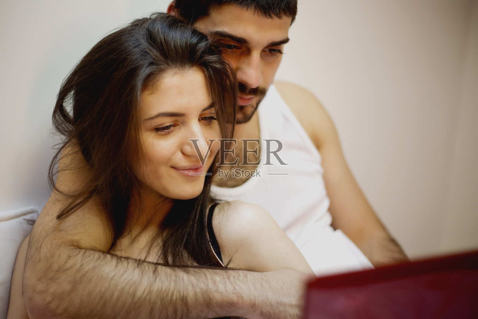 一对年轻夫妇在卧室的床上拥抱照片摄影图片