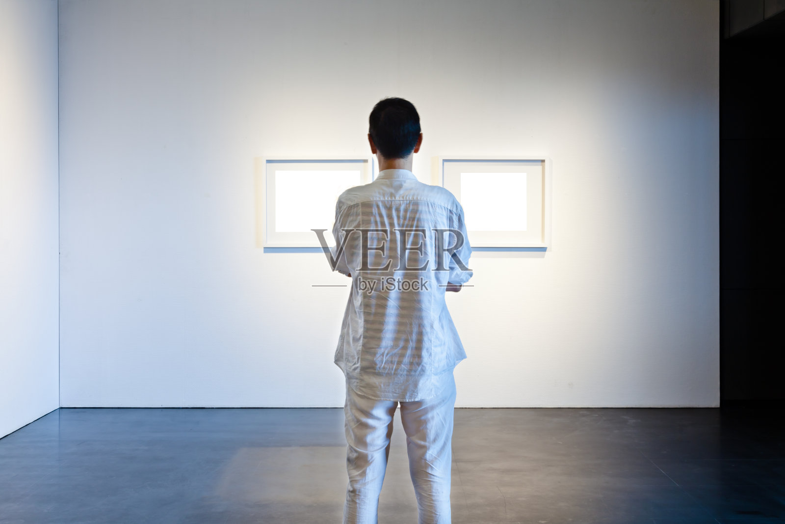 一个人在画廊里看白色的画框照片摄影图片