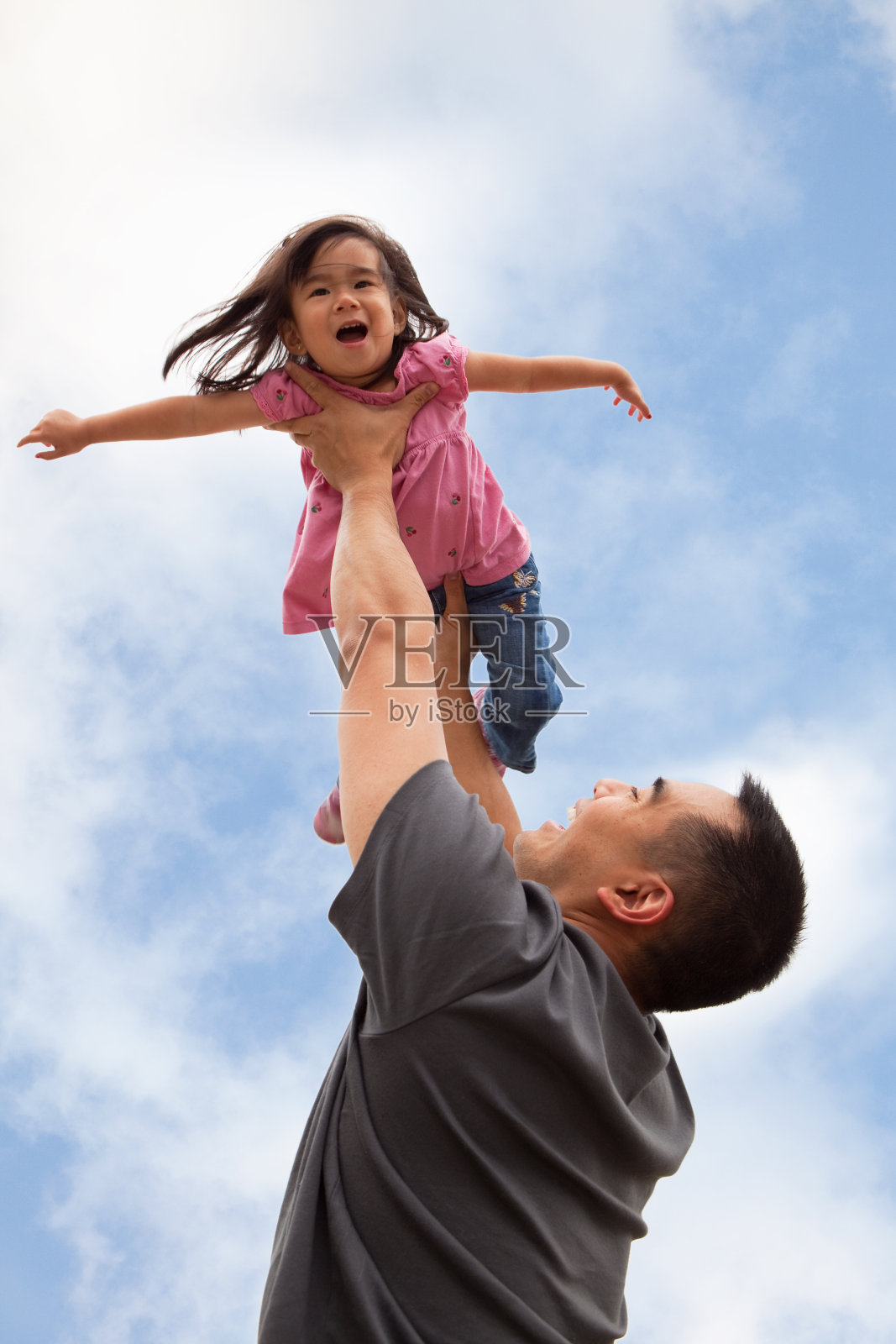 父亲像飞机一样把女儿举在空中照片摄影图片