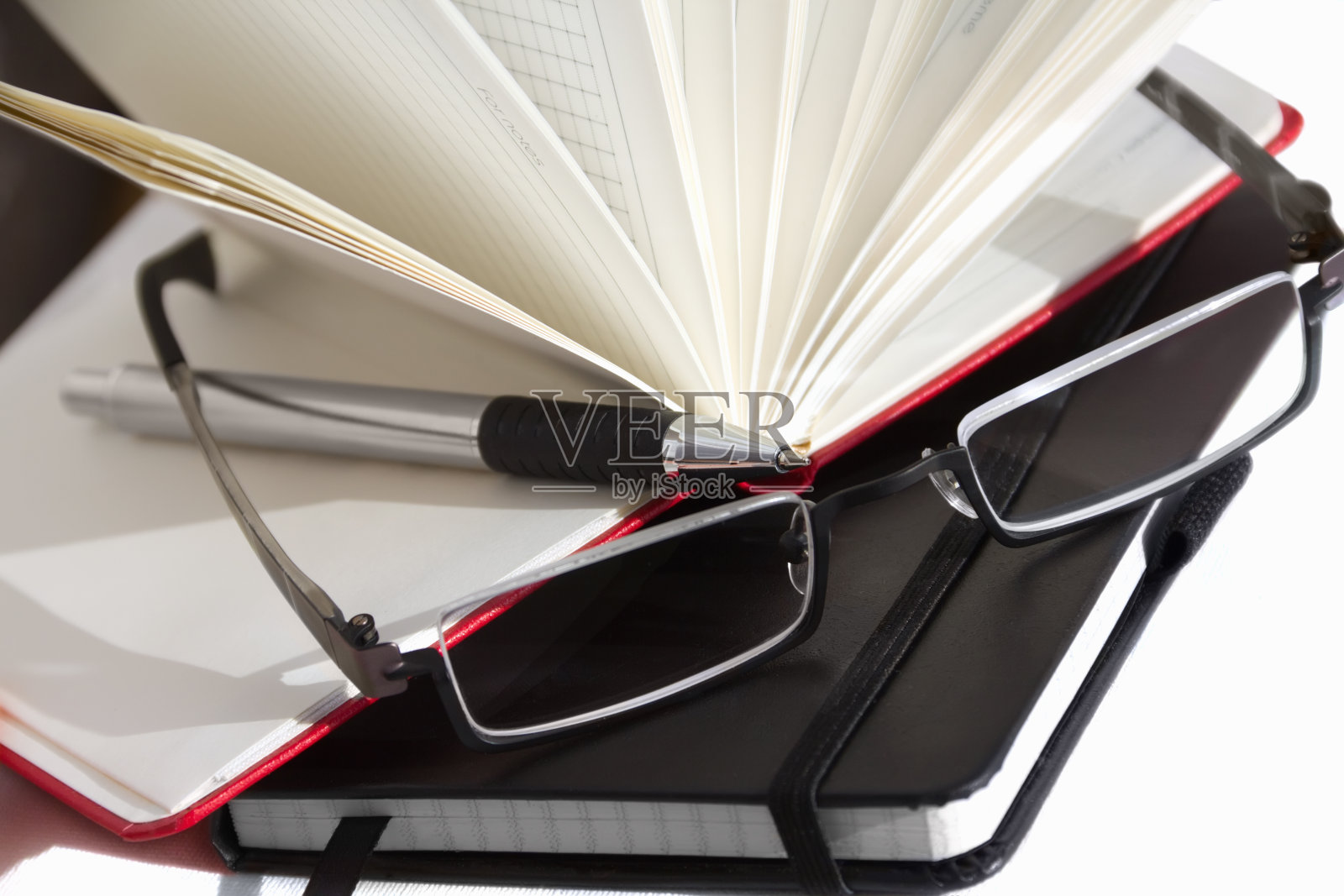 电脑上有带钢笔和眼镜的红色笔记本照片摄影图片
