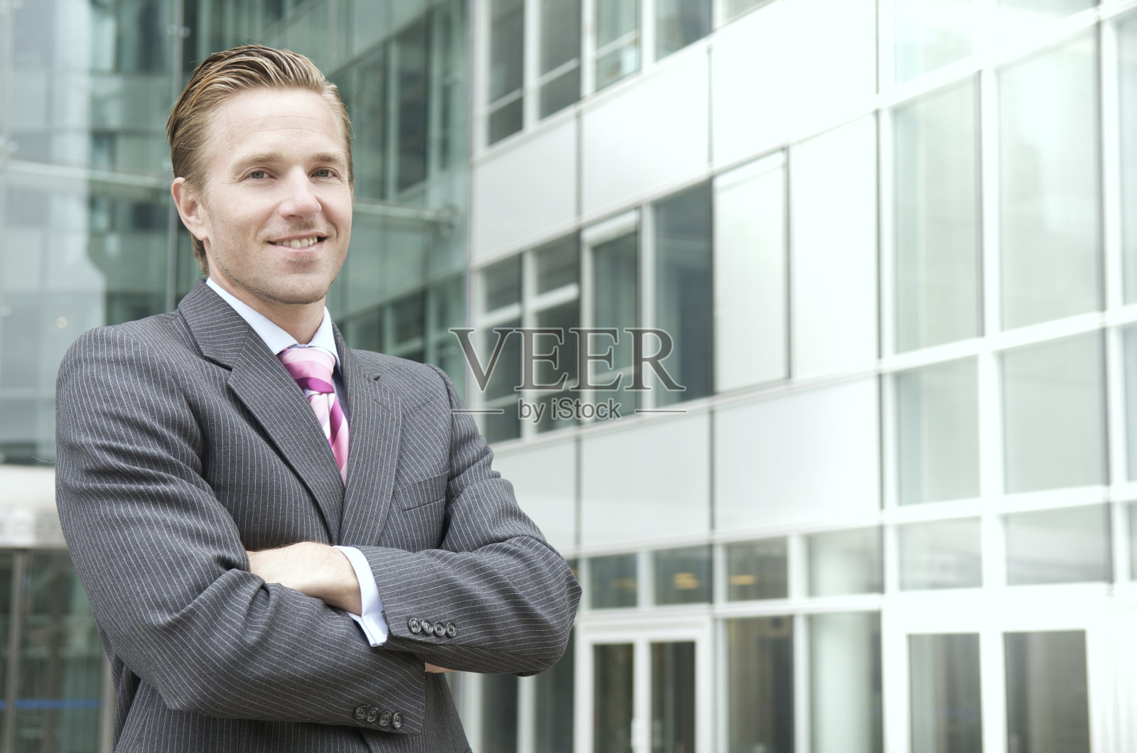 一名商人双臂交叉站在办公室外照片摄影图片