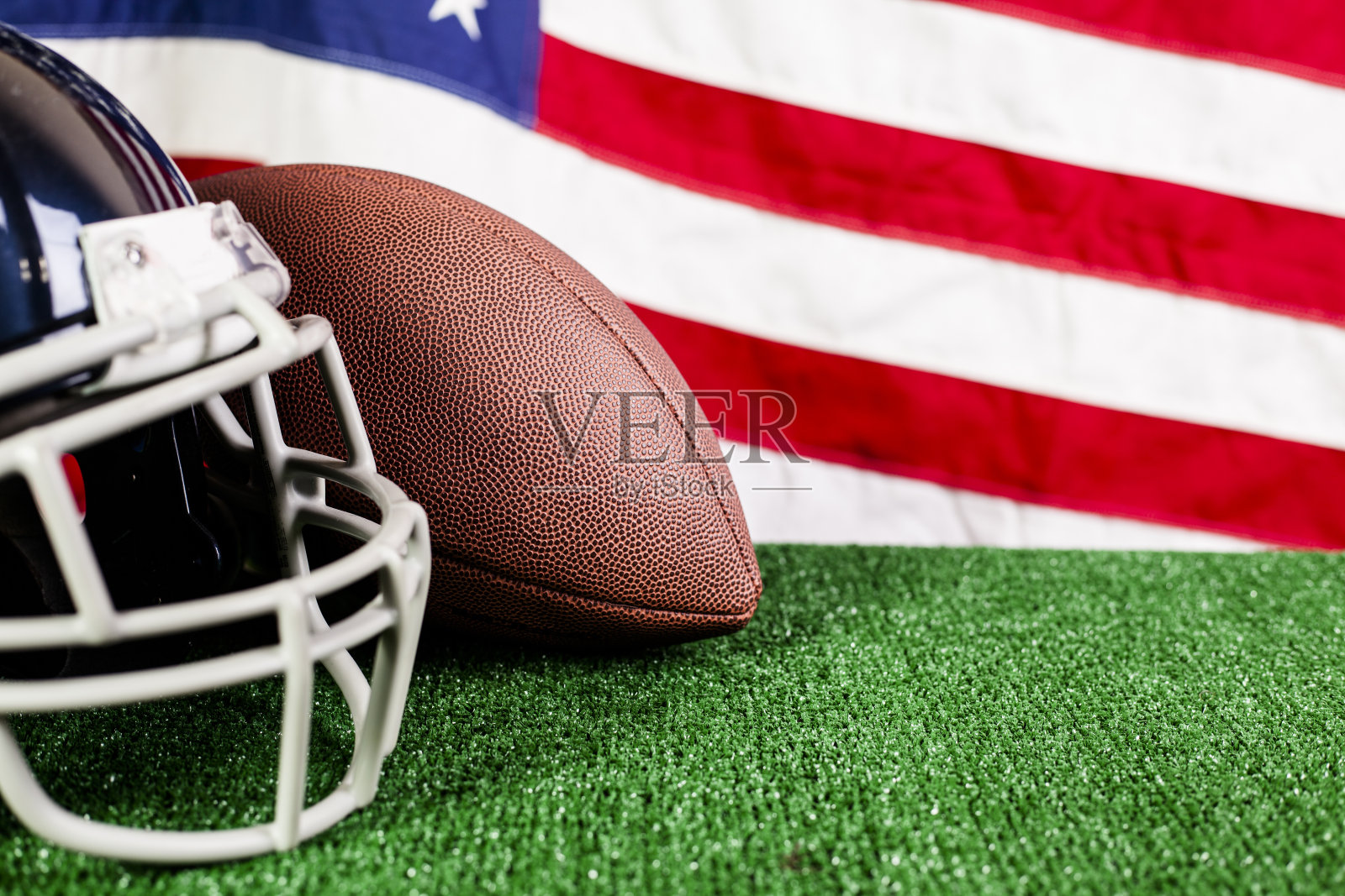 美式足球，头盔，绿色的球场草皮与美国国旗。照片摄影图片