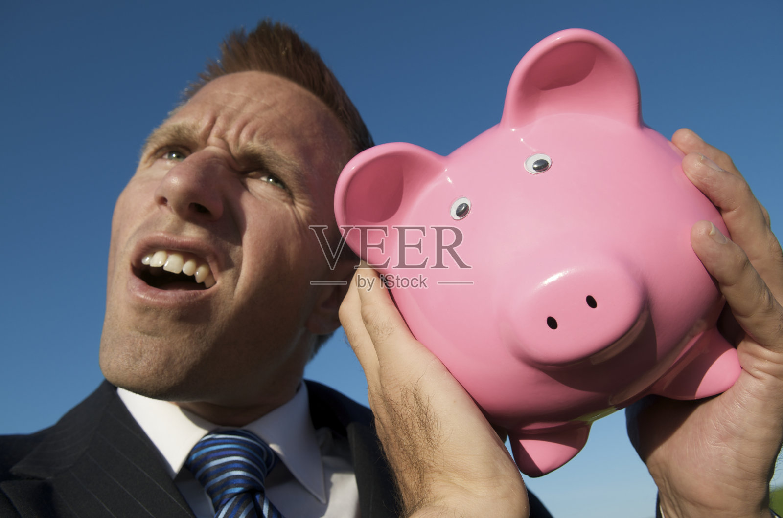 商人摇动粉色储蓄罐照片摄影图片