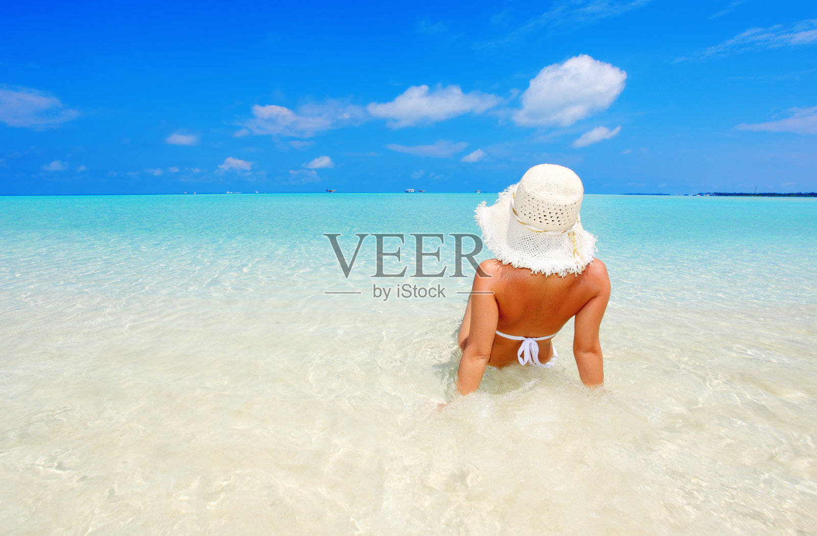 坐在海边的年轻女子。照片摄影图片