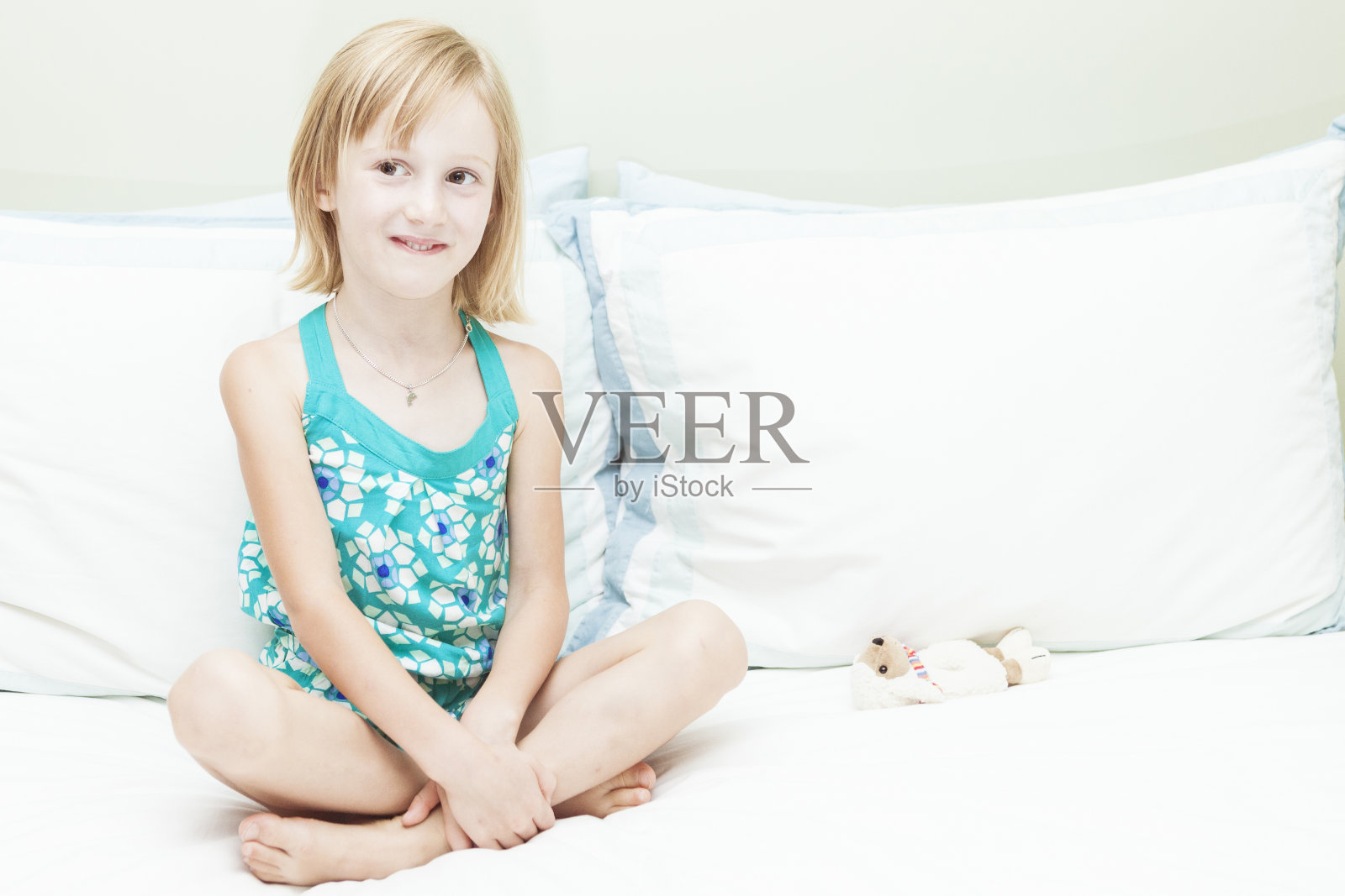 小女孩坐在床上。照片摄影图片