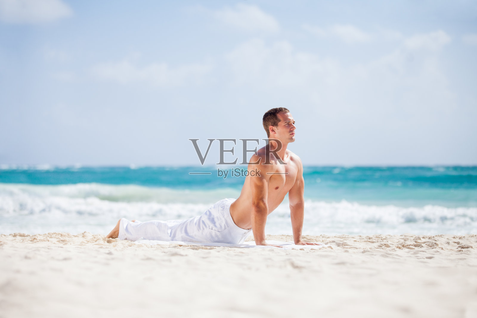 年轻的健康男子伸展在美丽的白色海滩。照片摄影图片