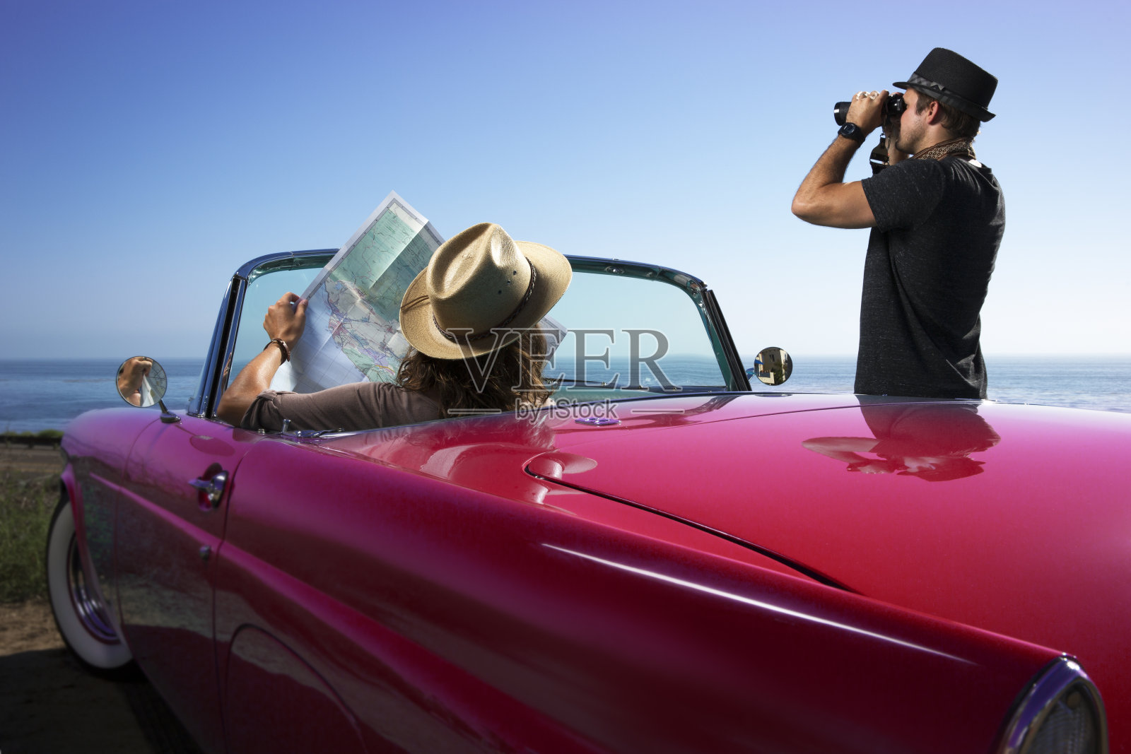 一对夫妇坐在蓝色敞篷车里看地图照片摄影图片
