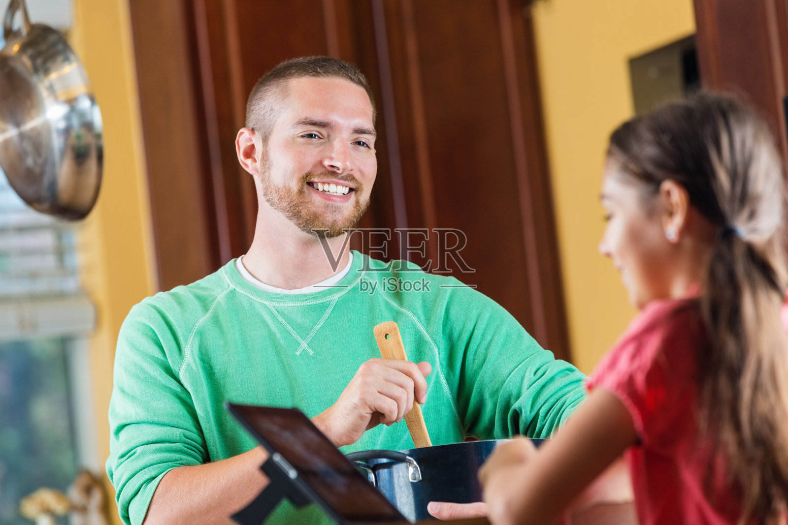 父亲在做饭，小女儿在用平板电脑照片摄影图片