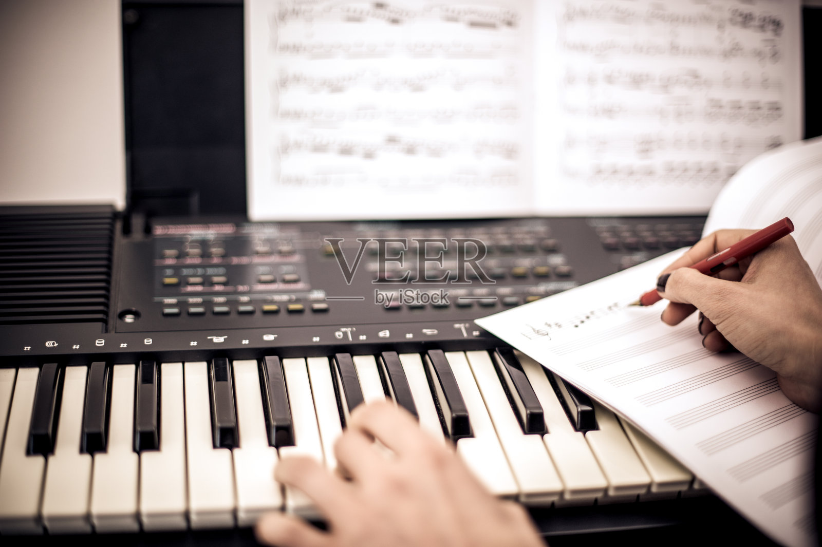 年轻女子一边弹键盘一边写音符照片摄影图片