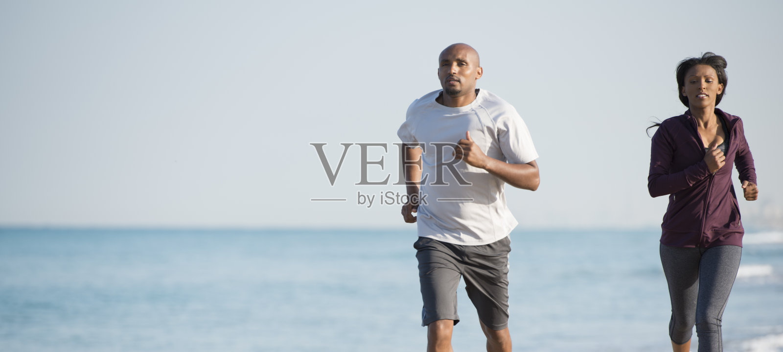 一对情侣在沙滩上跑步。照片摄影图片