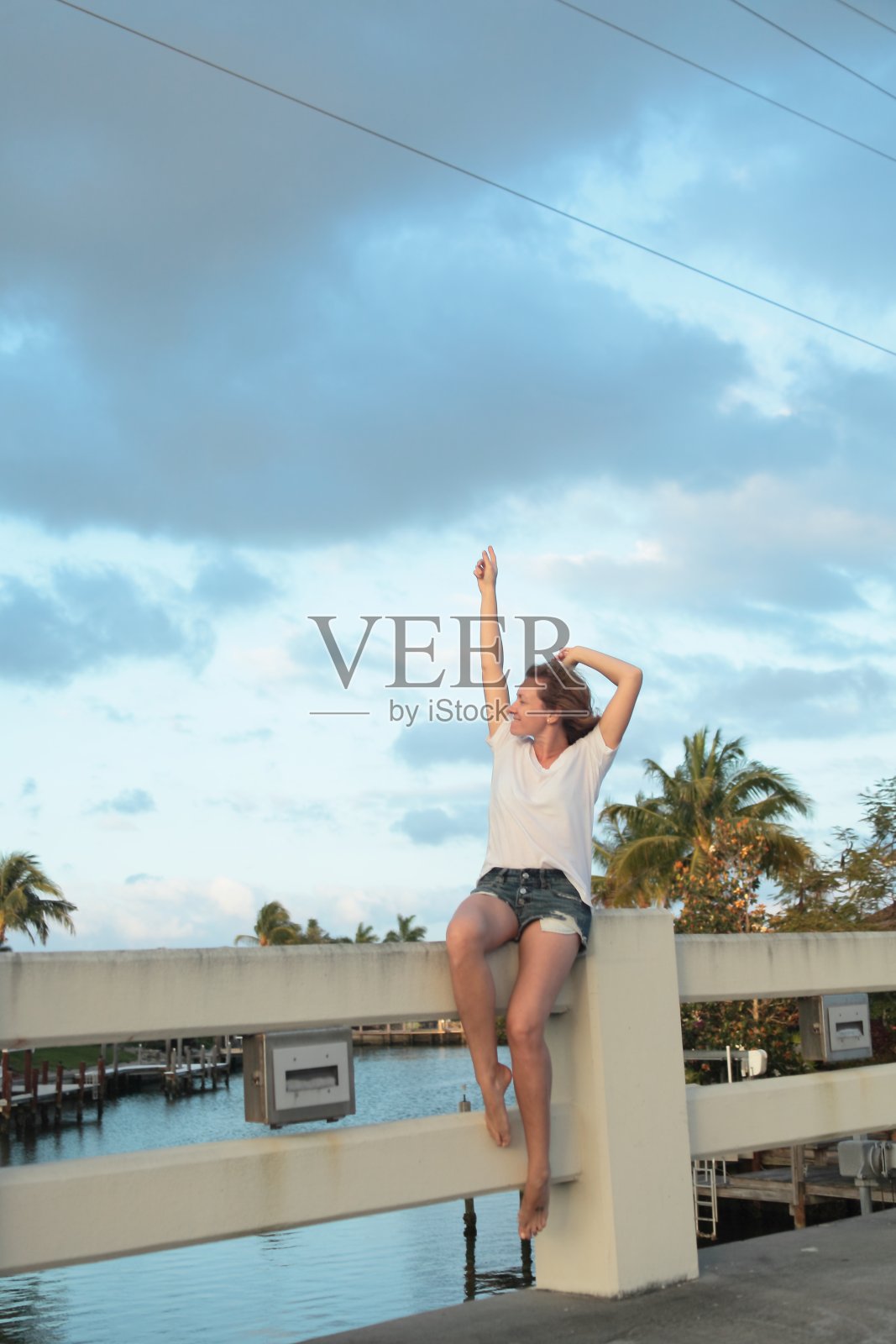 年轻女子正坐在桥上。照片摄影图片