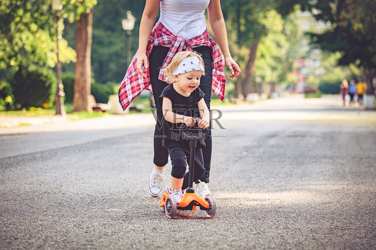 小女孩在公园里玩，开着推滑板车。照片摄影图片