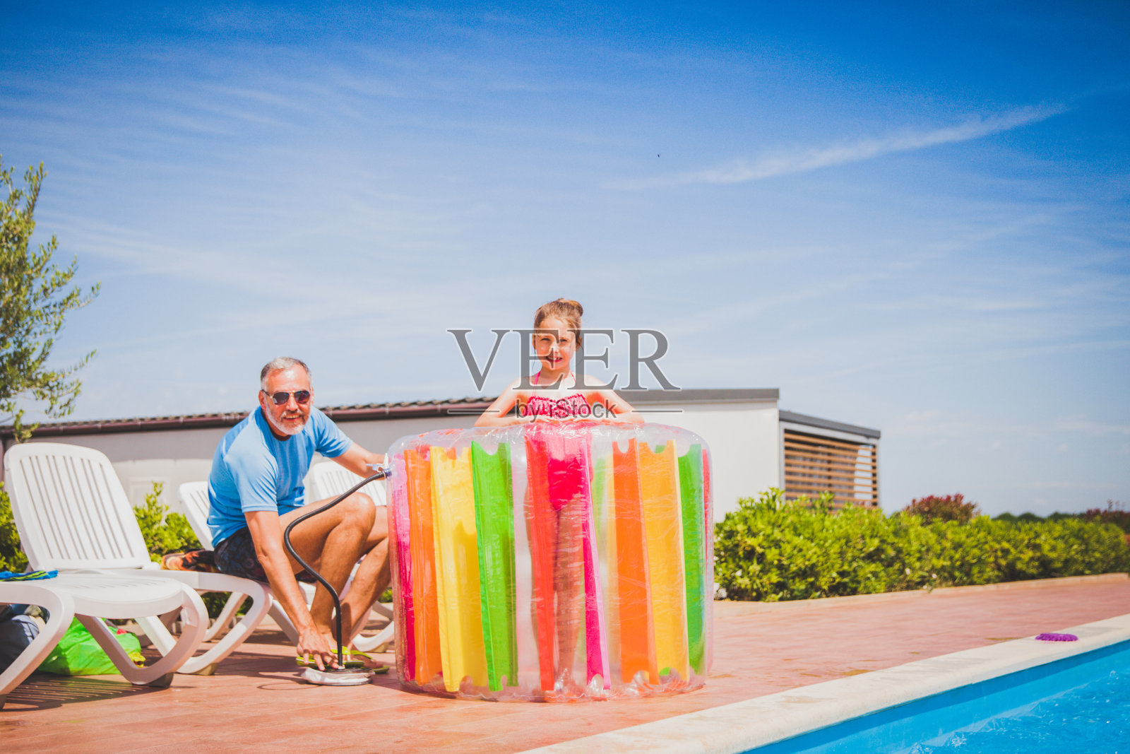 在游泳池做白日梦-父亲抽水跟玩具给他的女儿照片摄影图片