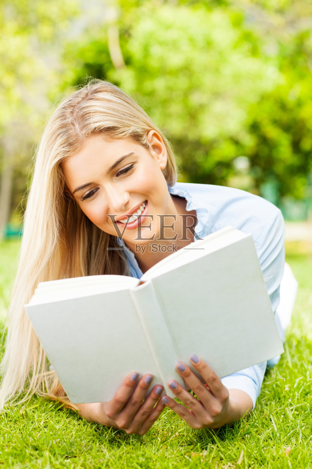 年轻女子在公园读书。照片摄影图片