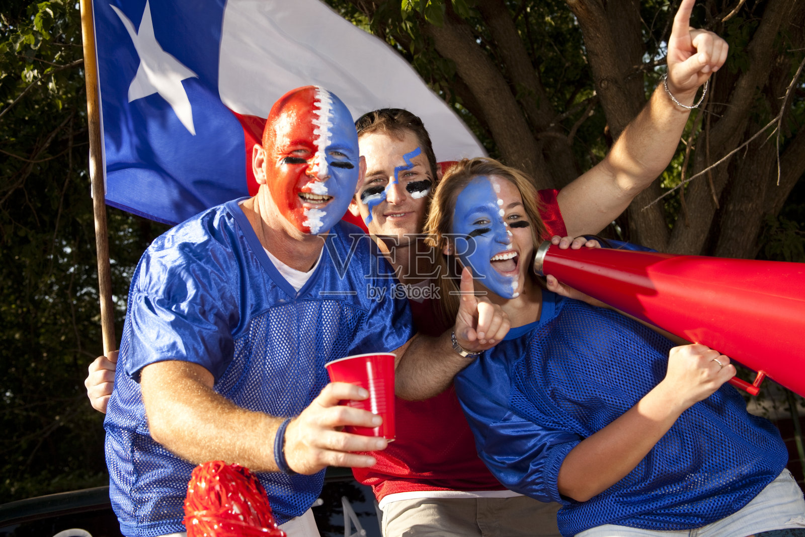 一群兴奋的足球迷在车尾野餐会上大喊大叫。德克萨斯州。照片摄影图片