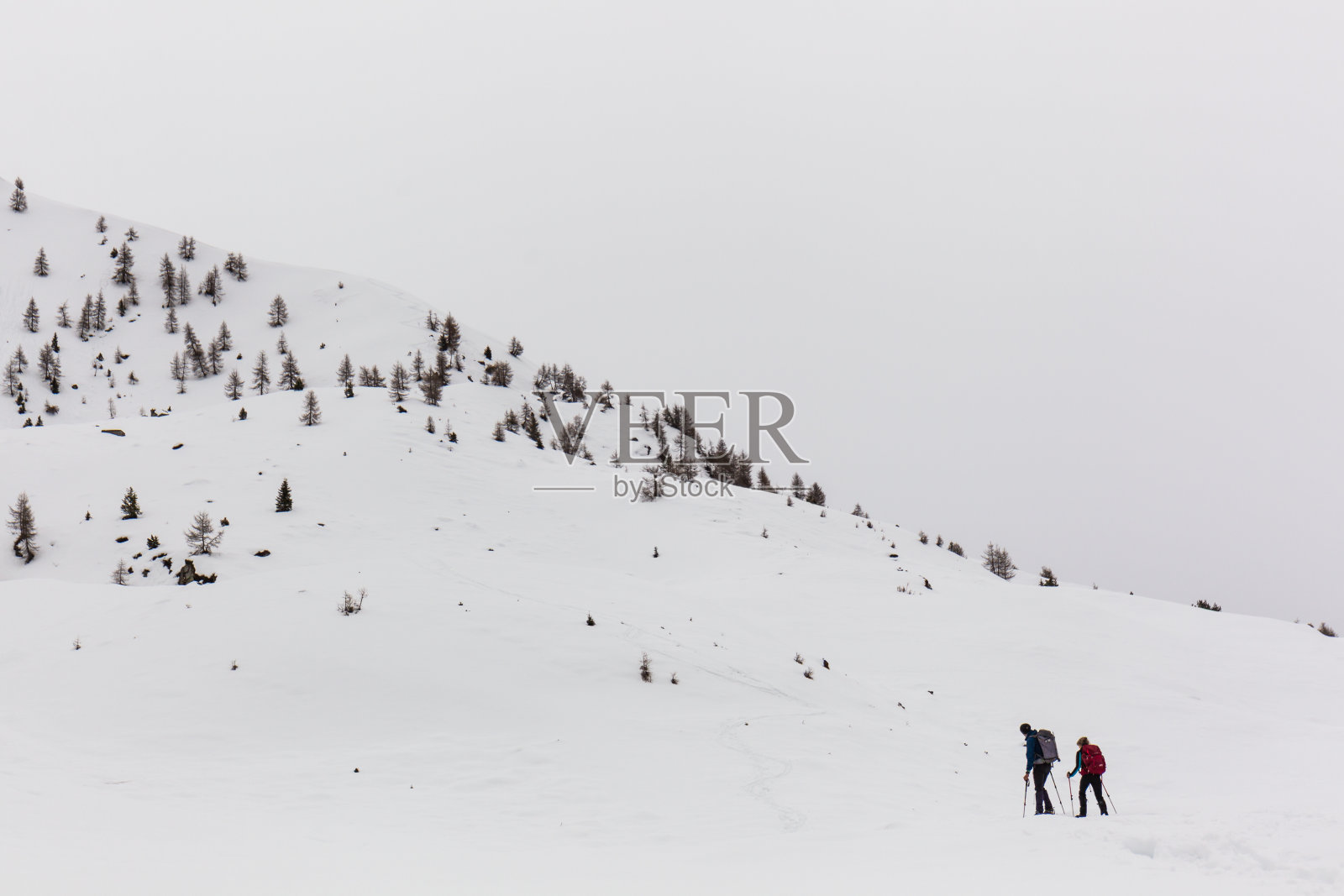 穿着雪鞋在白雪覆盖的山上行走的徒步者照片摄影图片