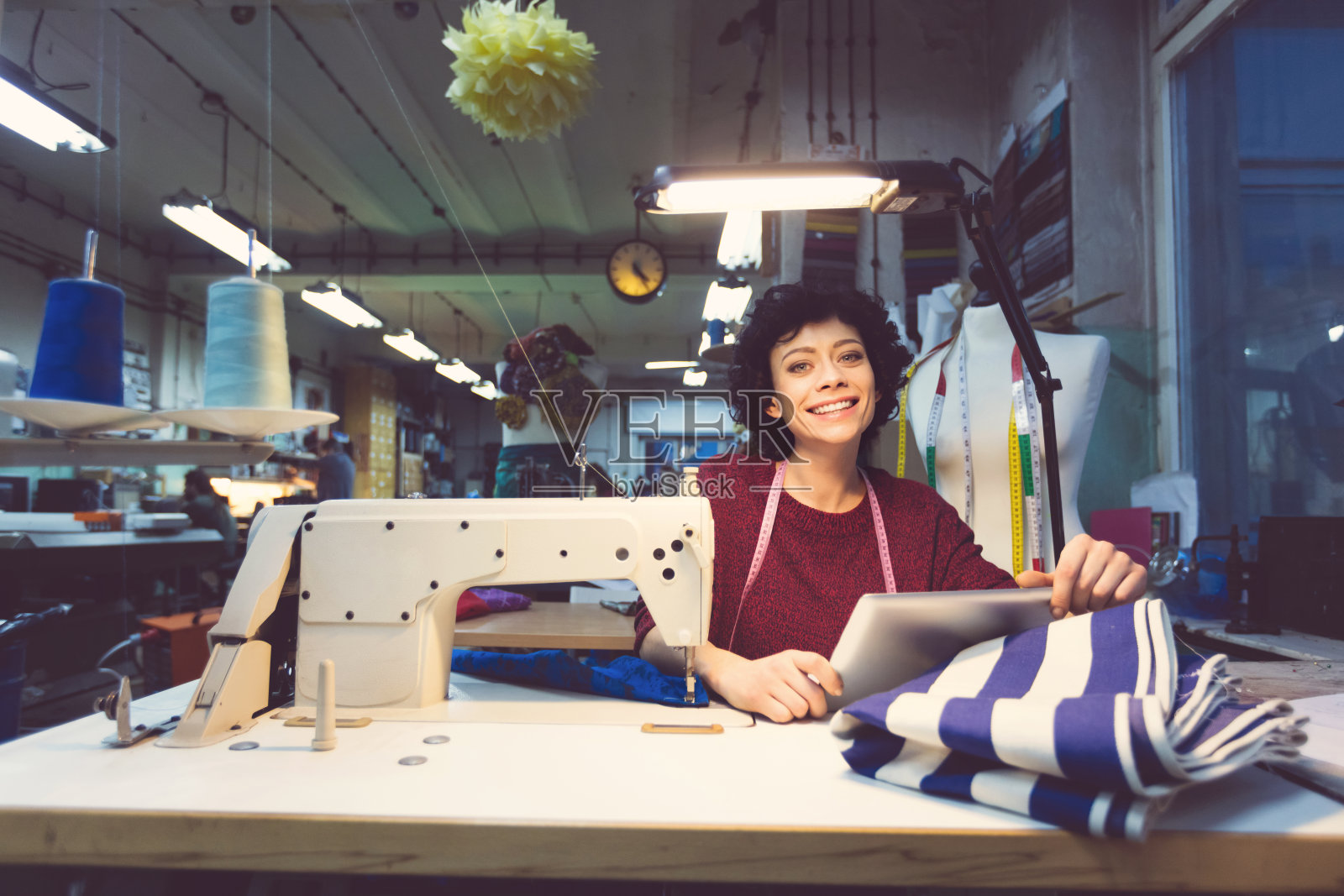 快乐的女裁缝工作，用着平板电脑照片摄影图片