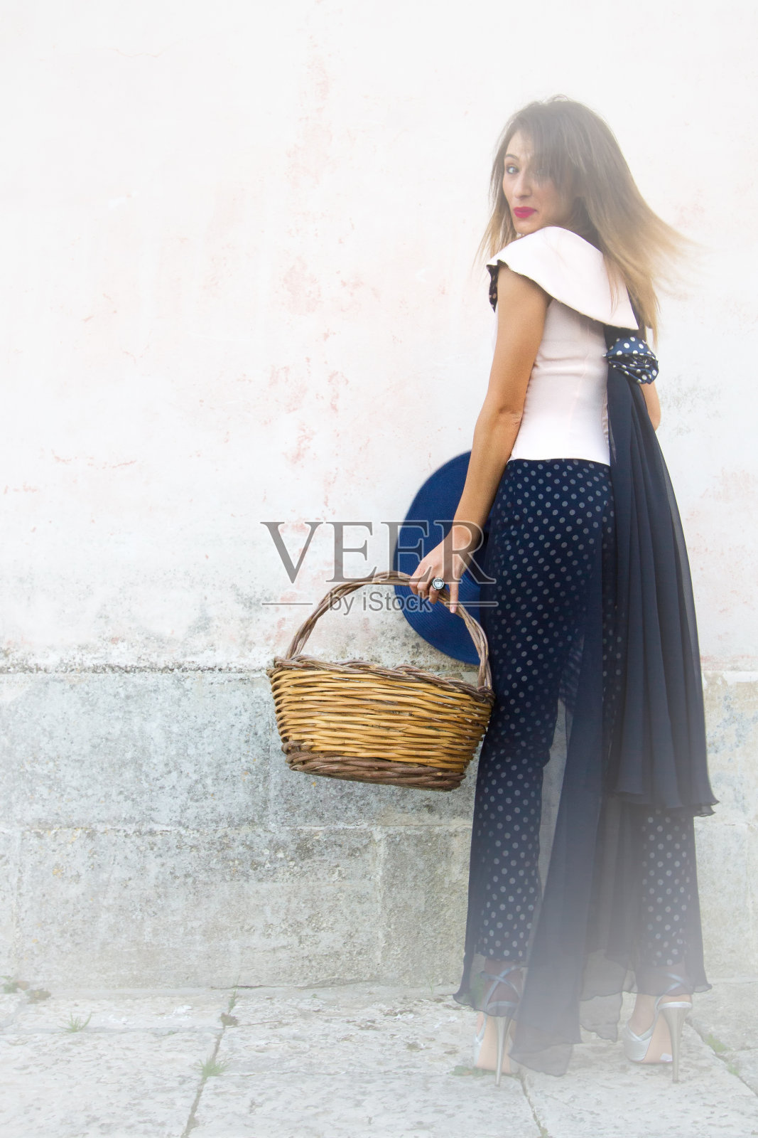 优雅的年轻女子柳条篮子，粉红色的墙背景照片摄影图片