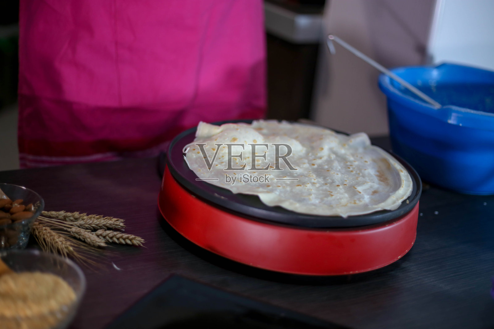 女孩倒了一勺面团做煎饼。在家做煎饼。照片摄影图片