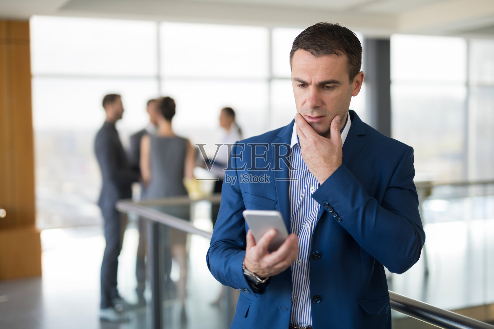 成熟的商人拿着手机看短信。照片摄影图片