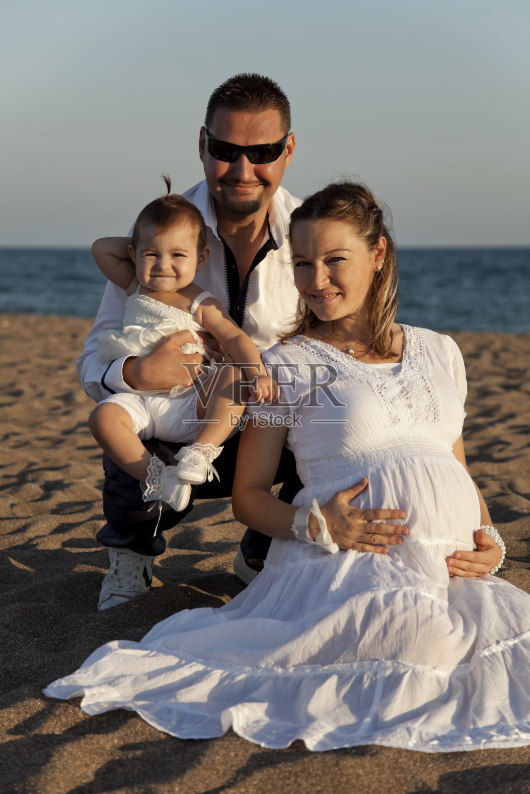 年轻的家庭在海滩摆姿势照片摄影图片