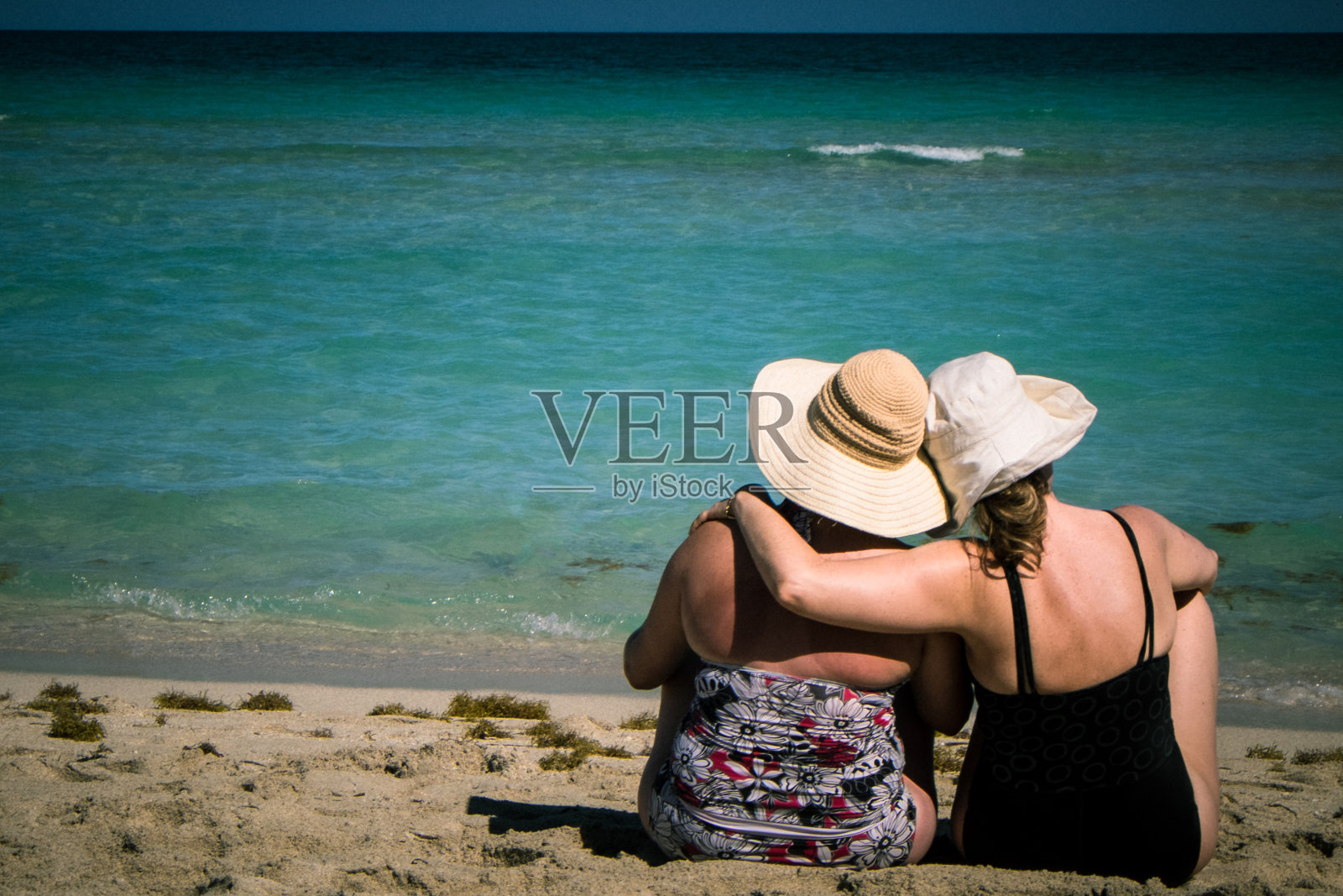 两个女人在海滩上展示她们的团聚照片摄影图片