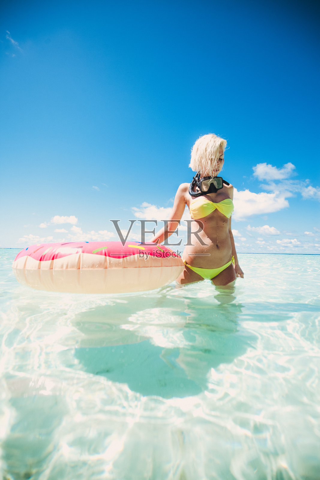 一名金发女子站在马尔代夫的浅水里，手里拿着通气管照片摄影图片