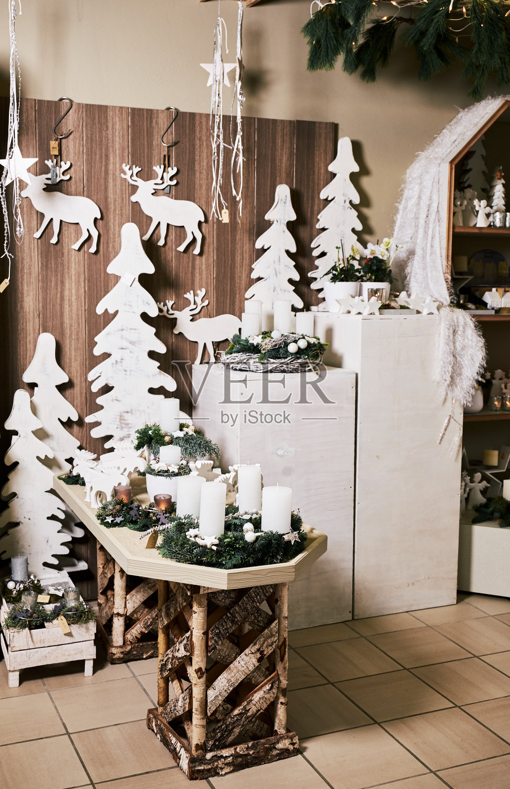 木桌上白色蜡烛、小鹿、星星和小冷杉枝的圣诞摆件照片摄影图片