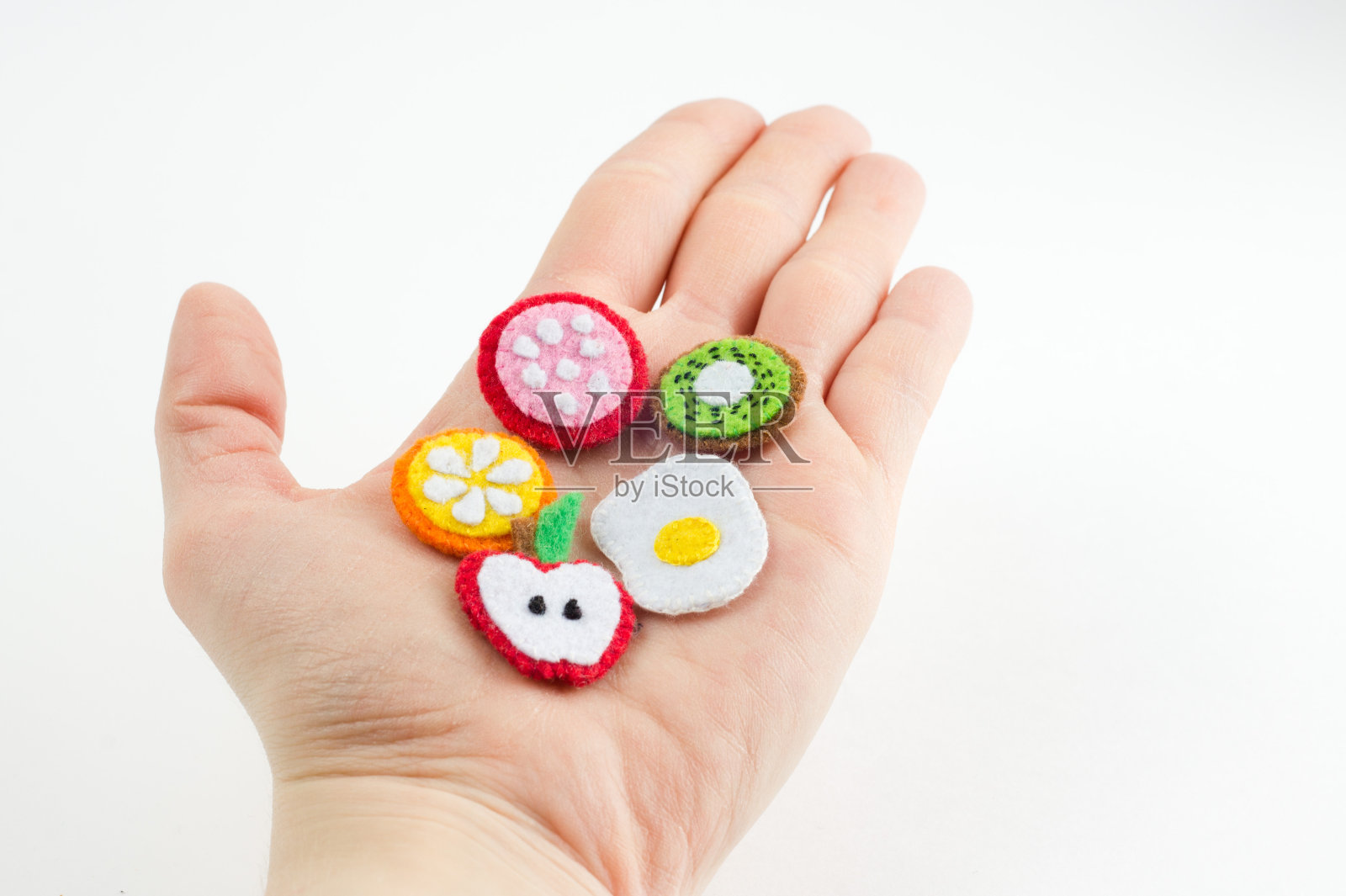 手工制作的水果和食物玩具，用毡制成，放在手掌上。手绣工艺品的特写照片摄影图片
