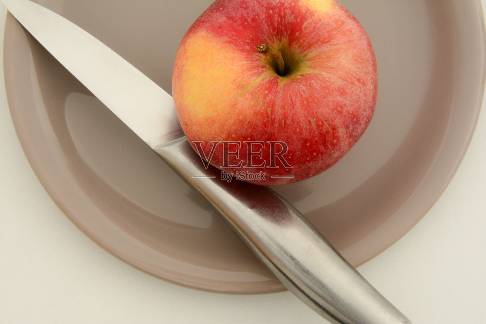 一个红苹果，用刀放在盘子里照片摄影图片