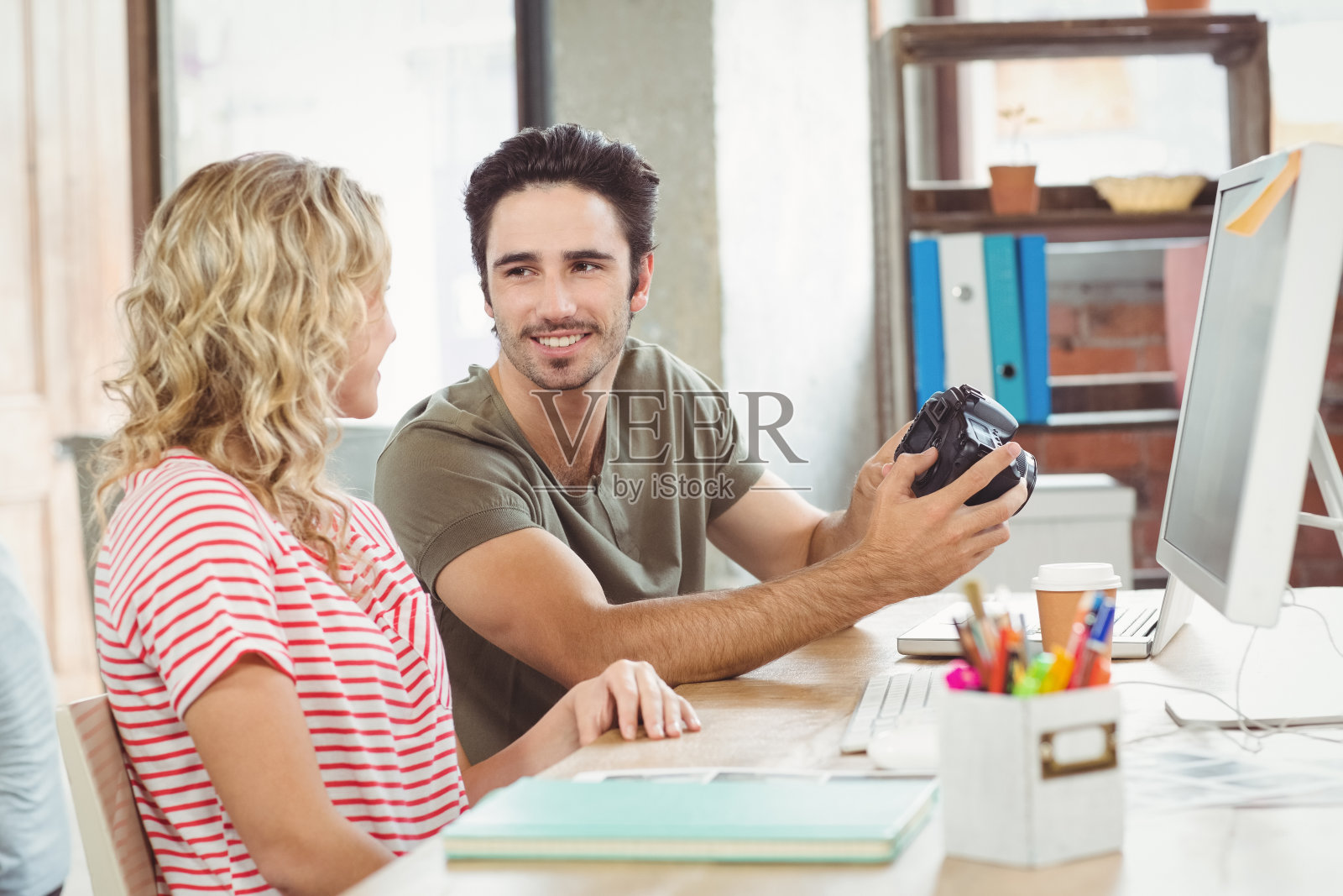 商人拿着数码相机在办公室与同事讨论照片摄影图片