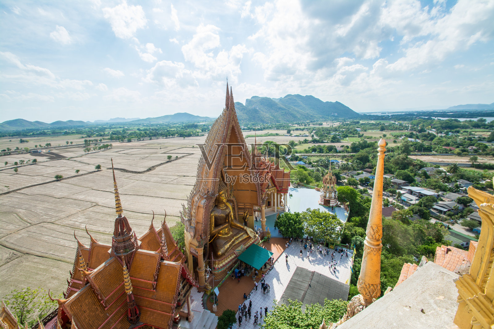 从宝塔俯视，金色的佛像与稻田和山的背景，Wat Tham Sua(老虎洞寺庙)，Kanchanburi，泰国照片摄影图片