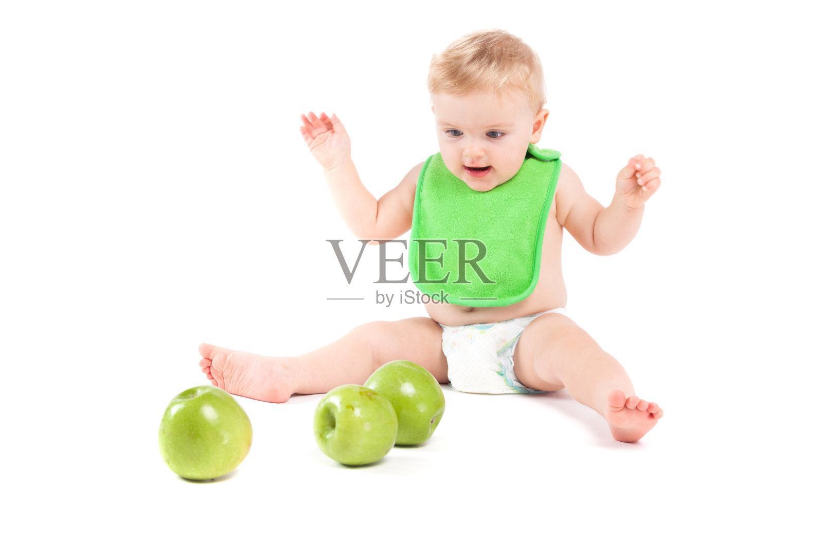 穿着绿色围兜的可爱快乐的小男孩玩苹果照片摄影图片