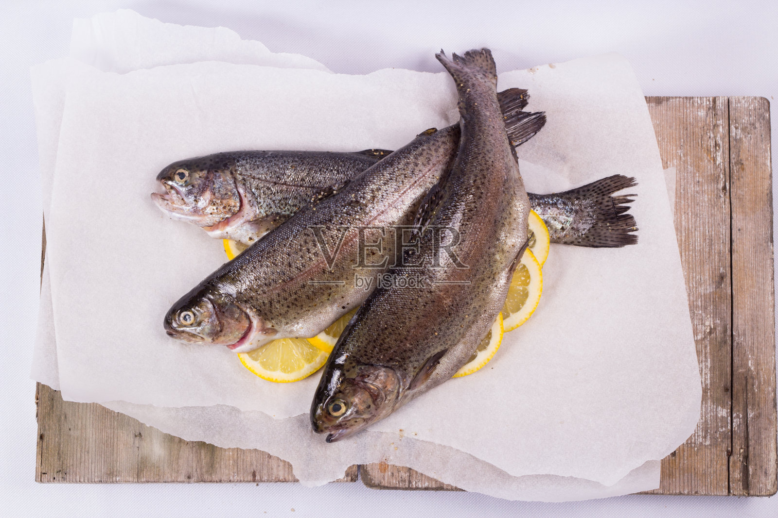 三个生鳟鱼在纸上照片摄影图片