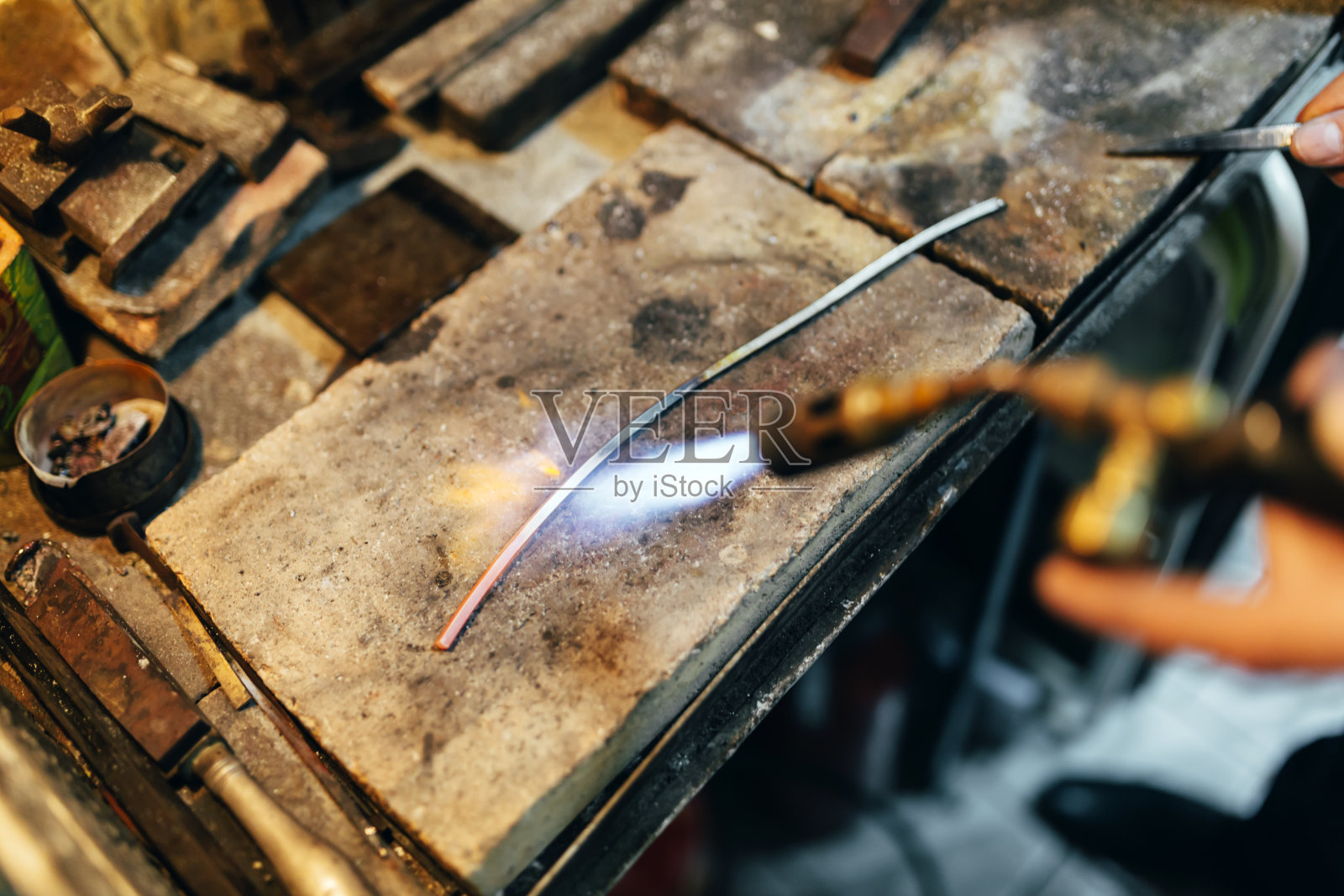 珠宝商通过加热来加工金属棒照片摄影图片