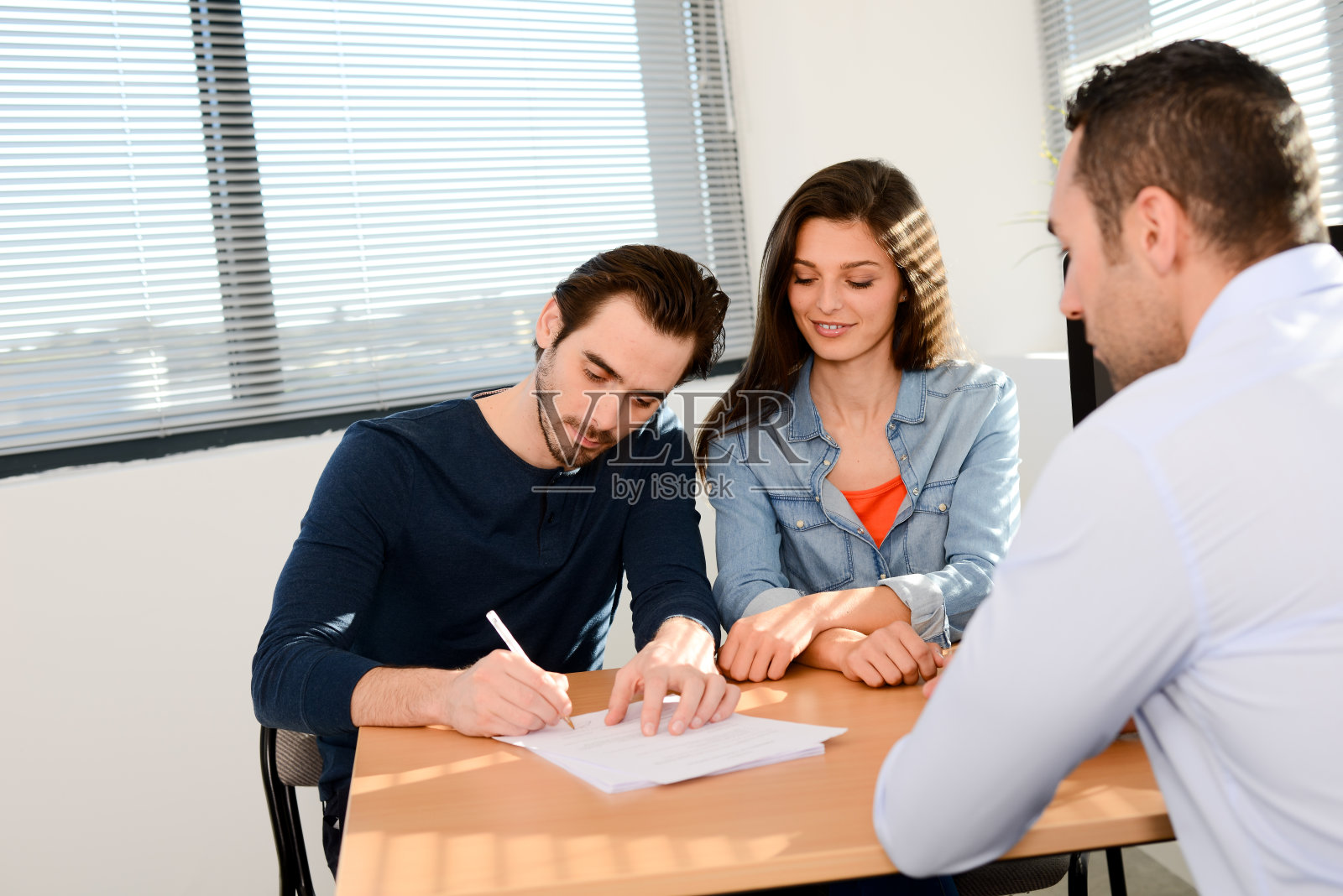 幸福的年轻夫妇在办公室与商人做生意购买协议合同签字照片摄影图片