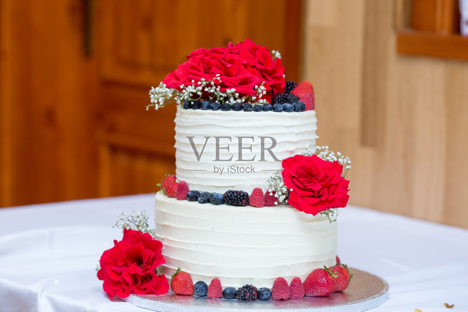 两层生日奶油和浆果蛋糕，装饰新鲜的红玫瑰，白色和红色调色板，特写，选择性聚焦照片摄影图片