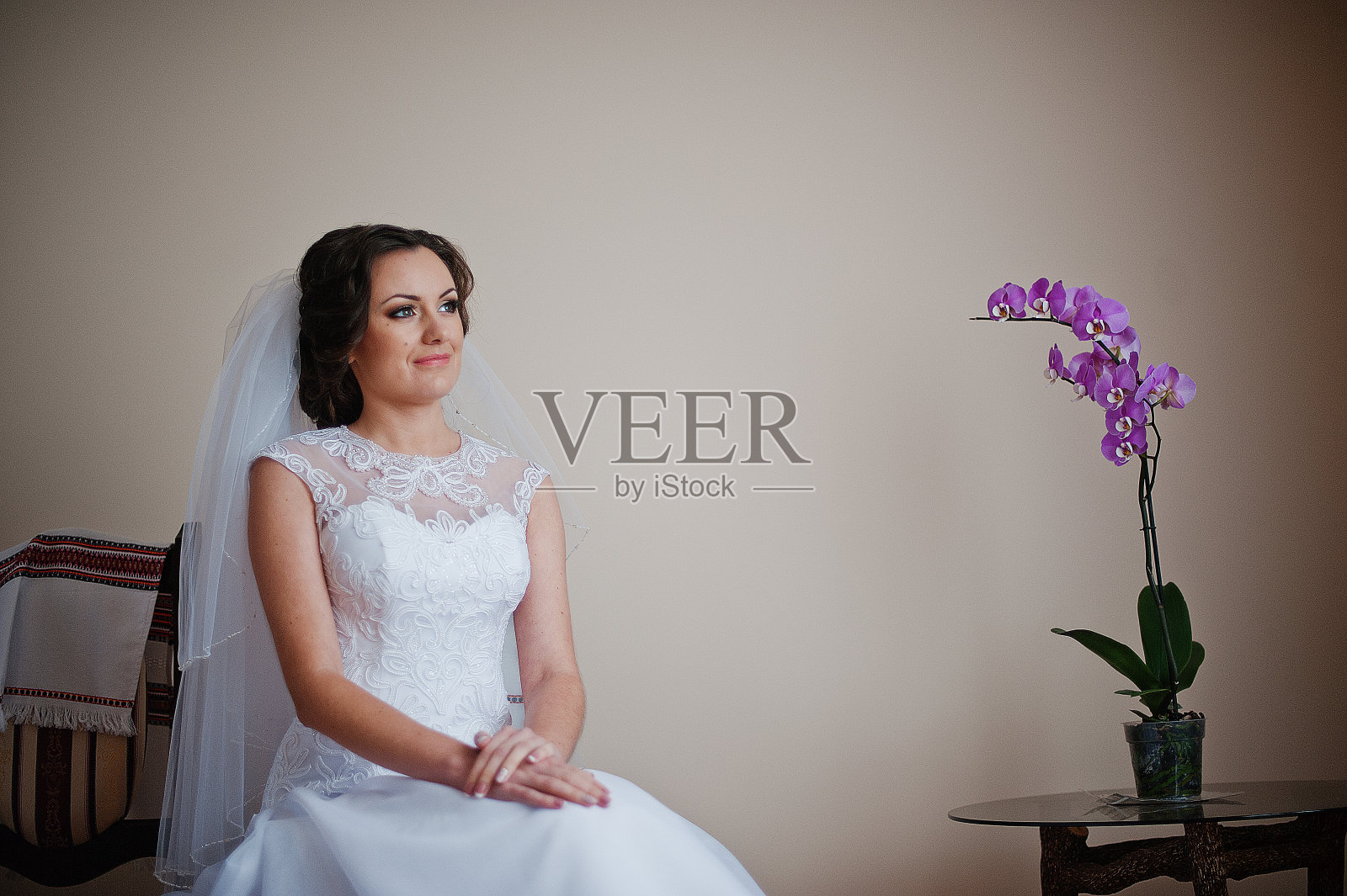 美丽的年轻新娘穿着时尚的礼服坐在椅子上照片摄影图片