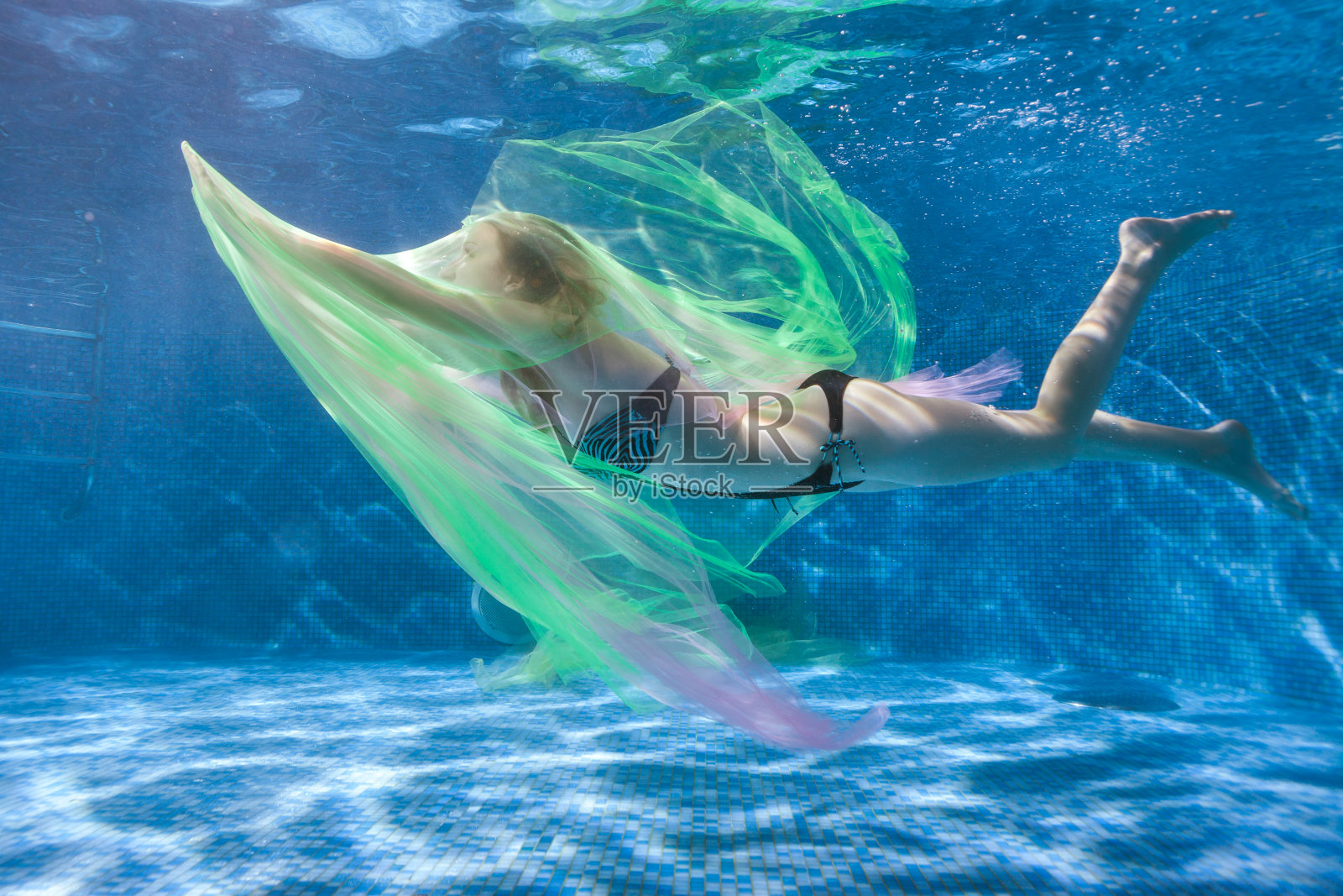 女人用水玩弄着透明的织物。照片摄影图片