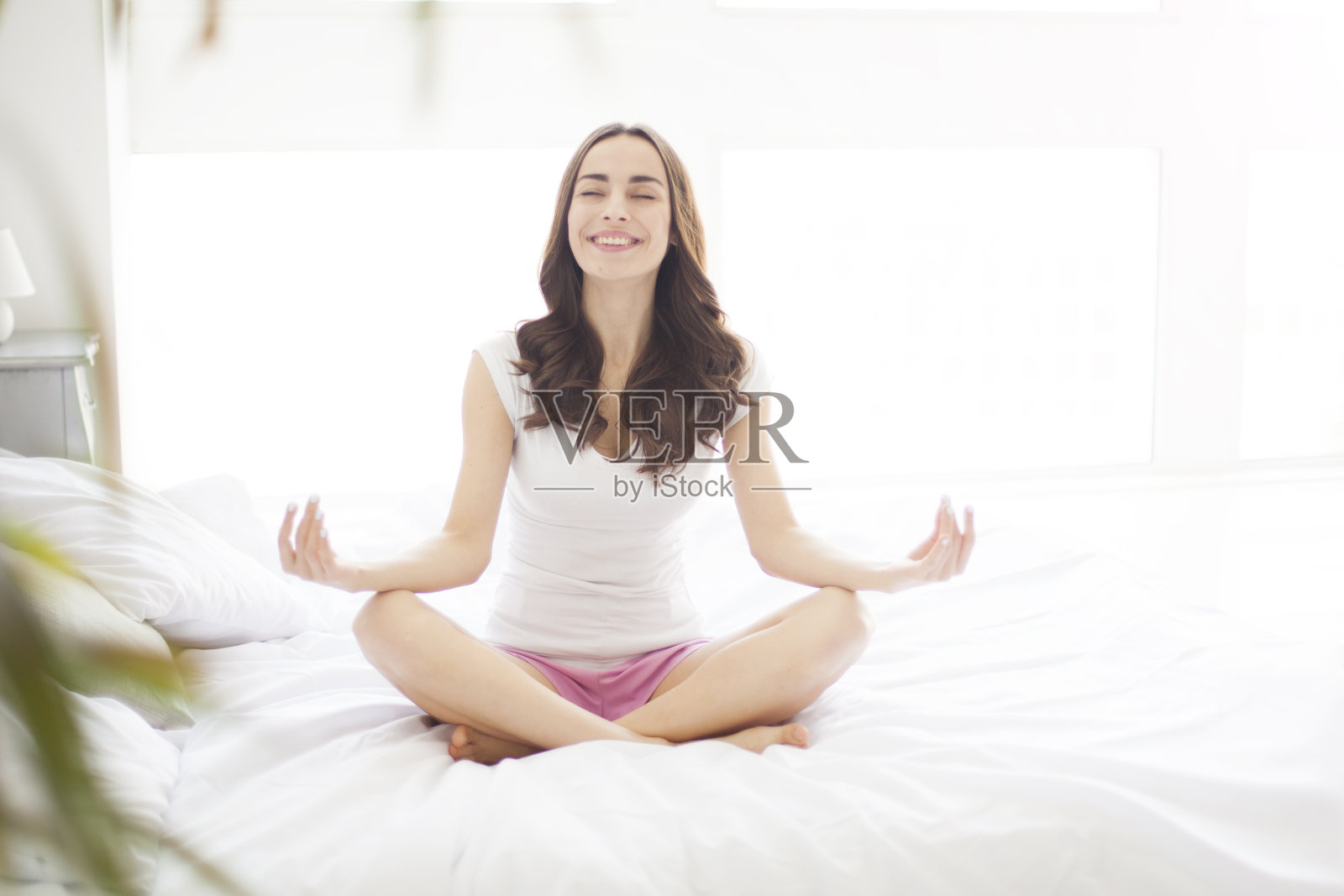 迷人的女人在卧室里莲花姿势。放松照片摄影图片