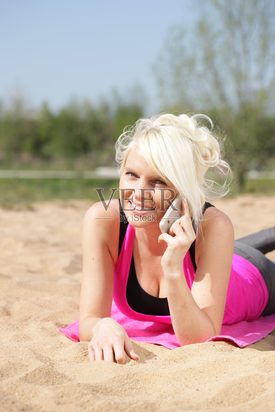 在海滩上玩手机的快乐女人照片摄影图片