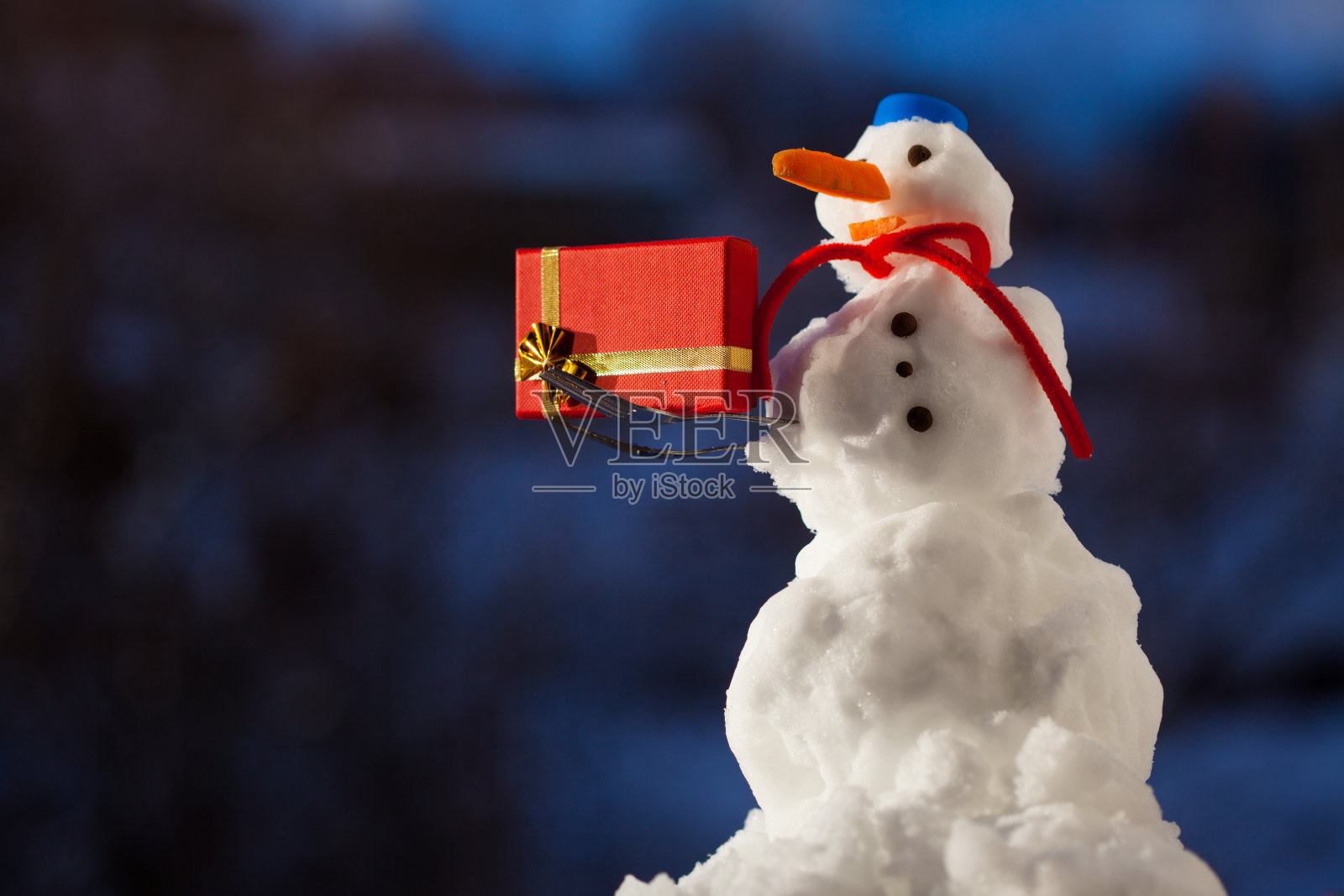 快乐小雪人带着圣诞礼盒在户外。冬天的季节。照片摄影图片