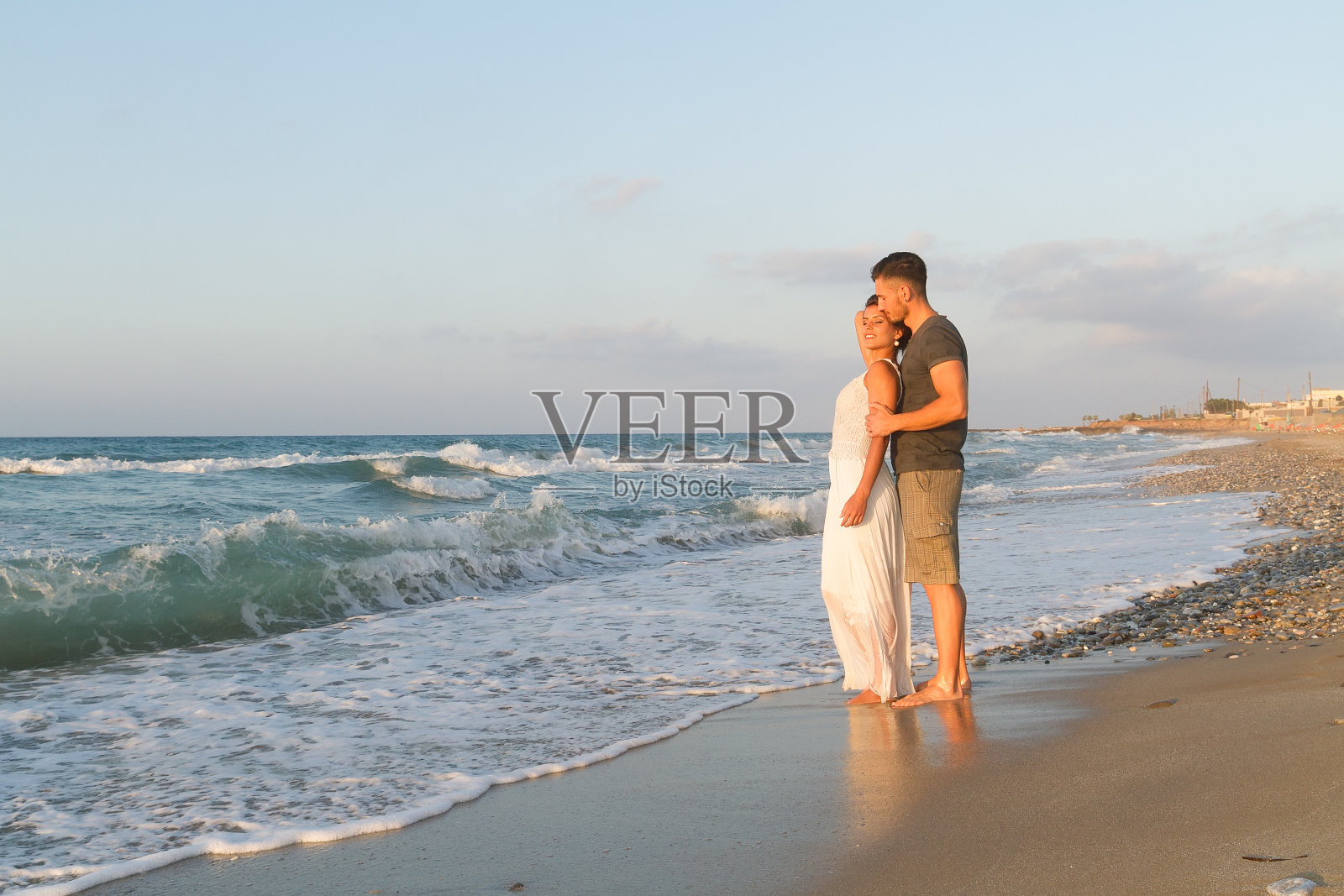 年轻夫妇喜欢在黄昏时分在雾蒙蒙的海滩上散步照片摄影图片