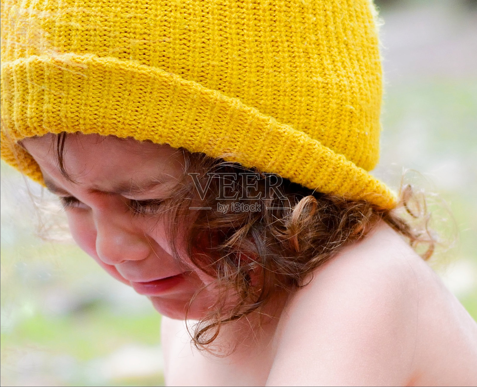 黄色无檐帽上的卷发男孩在哭泣照片摄影图片
